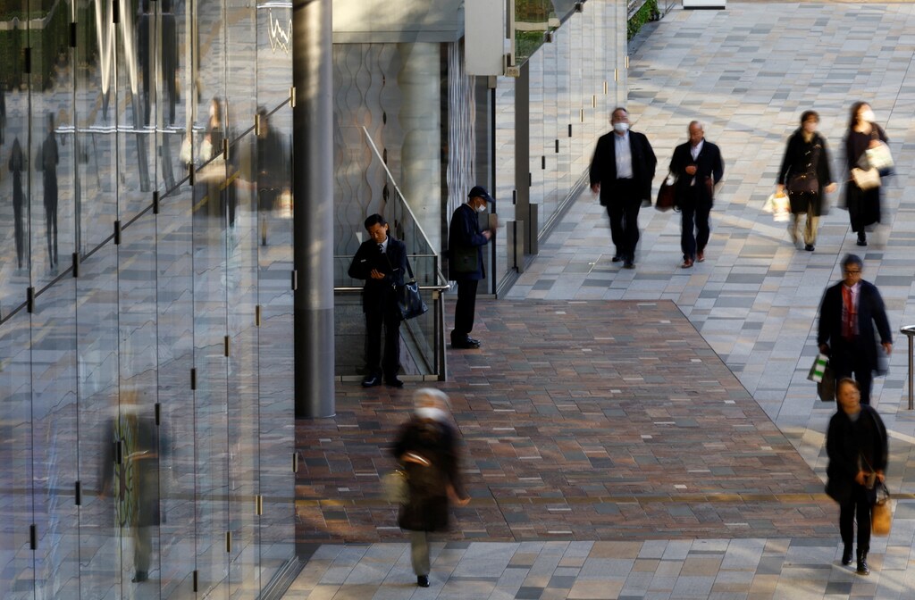 A man uses a laptop on a street at a business district in Tokyo, Japan.