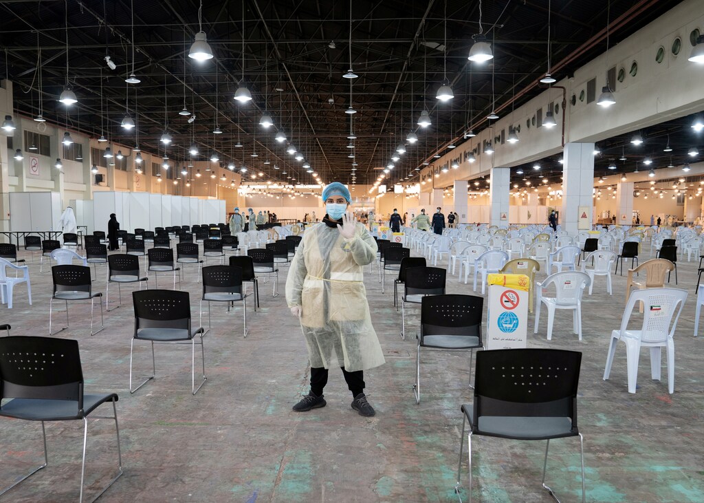 Un voluntario, que dirige a los visitantes en un centro de pruebas de coronavirus, hace gestos en el recinto de la Feria Internacional de Kuwait en Mishref (Kuwait) el 18 de marzo de 2020.