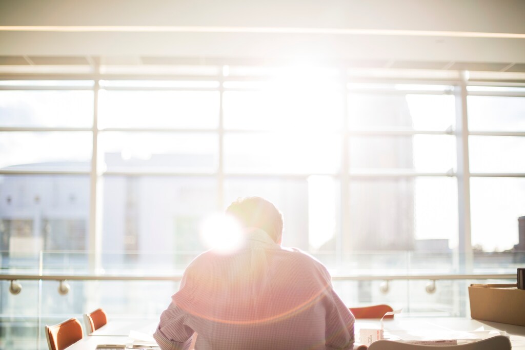 A man sitting at a desk in the sunshine.