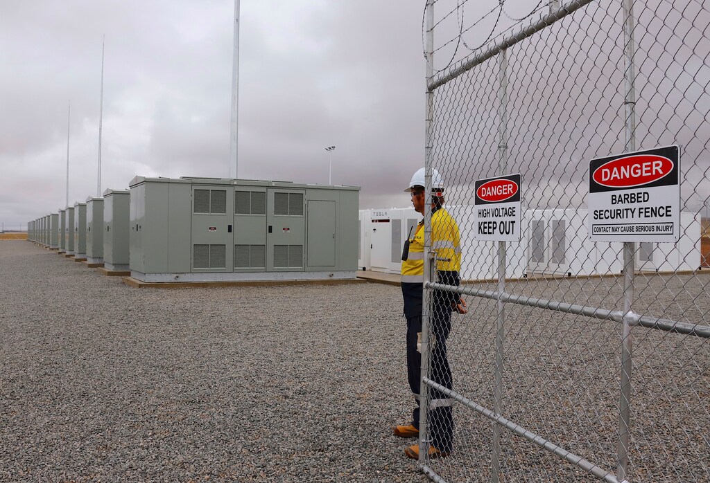 A worker stands at the main gate for the compound housing the Hornsdale Power Reserve, featuring the world's largest lithium ion battery made by Tesla, during the official launch near the South Australian town of Jamestown, in Australia, December 1, 2017. REUTERS/David Gray - RC1642836A20
