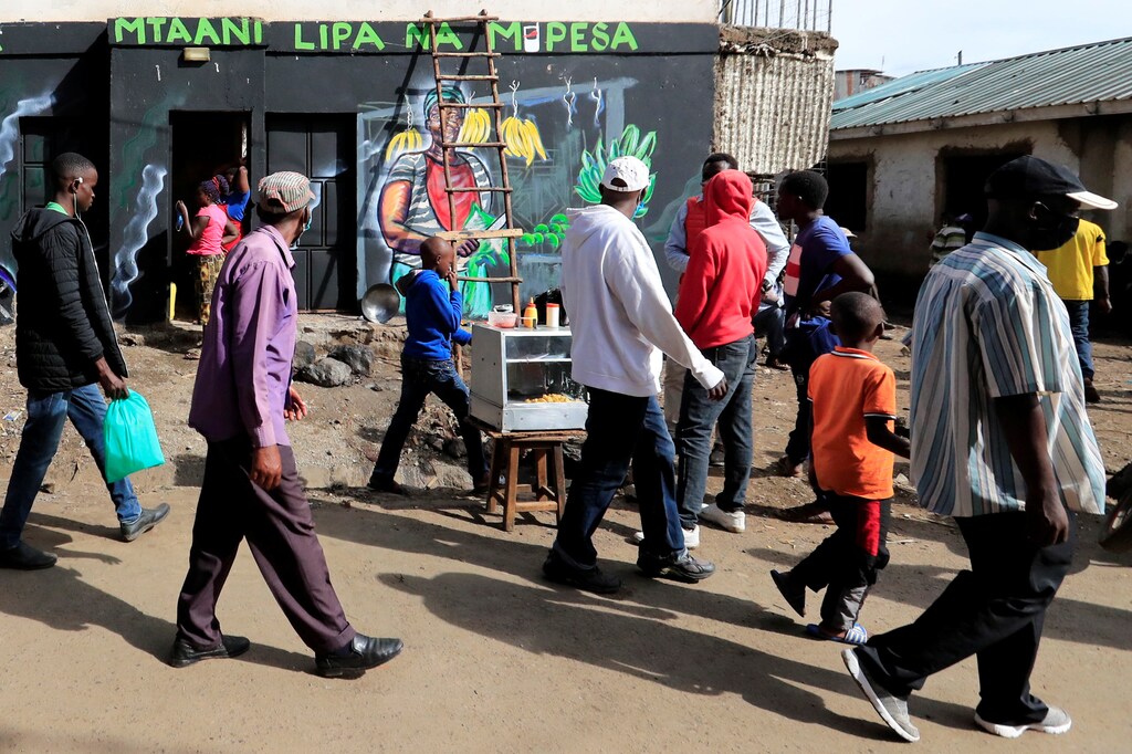 Residents walk past a mural advocating for retail M-Pesa mobile phone cashless payments as a measure against the spread of the coronavirus disease (COVID-19) in Nairobi, Kenya April 19, 2020. Picture taken April 19, 2020. REUTERS/Thomas Mukoya - RC288G9RF2H1