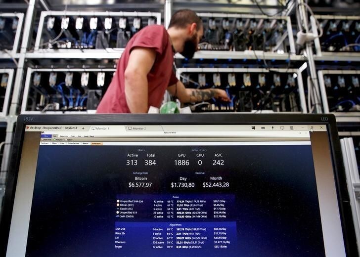 An employee works on Bitcoin mining computer as a PC screen shows the fluctuations in Bitcoin exchange rates at Bitminer Factory in Florence, Italy, April 6, 2018. Picture taken April 6, 2018. REUTERS/Alessandro Bianchi