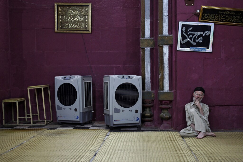 A man sits beside portable air coolers at a mosque inside the shrine of Sufi Saint Nizamuddin Auliya after evening prayers in New Delhi May 30, 2013.