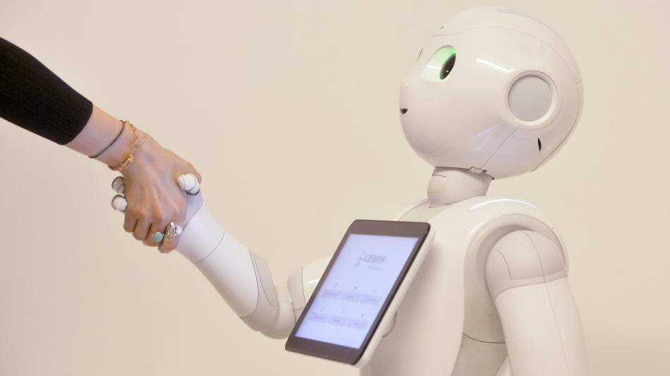 A robot and a human shaking hands.