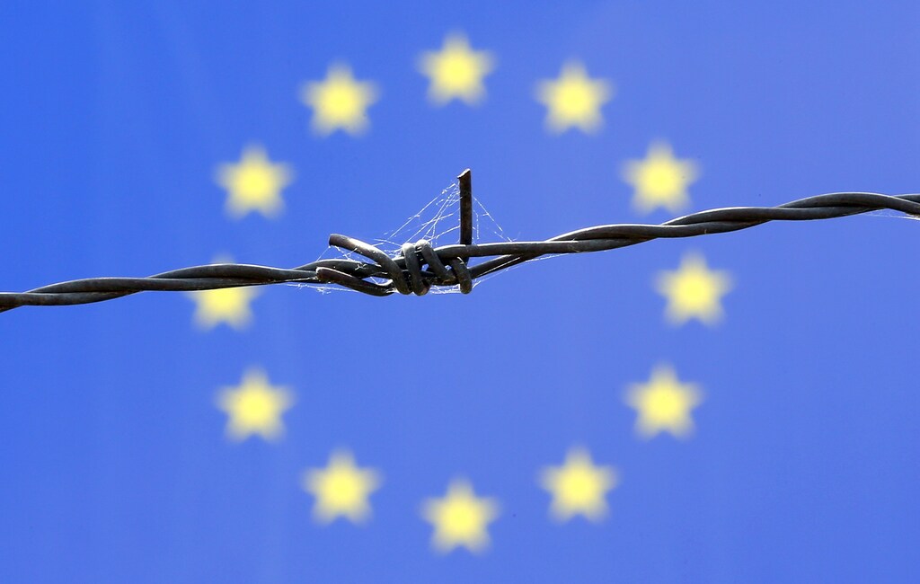 A barbed wire is seen in front of European Union flag in an immigration reception centre in Bicske, Hungary June 25, 2015. Austria threatened to reimpose controls on its Hungarian border and Britain considered adding security around the French port of Calais on Wednesday as divided EU leaders prepared to debate how to stem a flood of desperate migrants. Austria's warning about reinstating checks on its passport-free border with Hungary follows a refusal by Budapest to take in asylum seekers sent back to it by other member states under EU rules. Hungary says it no longer has the means to deal with a sharp increase in people streaming over its Balkan border - many from the Middle East, including via crisis-wracked Greece. REUTERS/Laszlo Balogh - GF10000138877