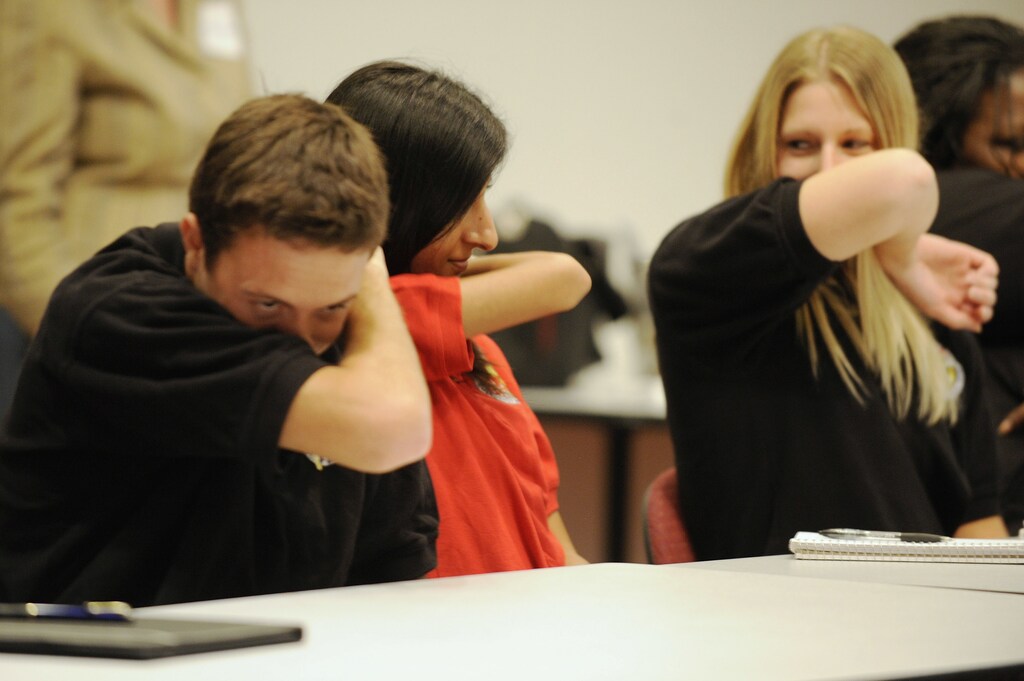 People practice coughing into their sleeves as a way to try to control the spread of the H1N1 swine flu virus, during a meeting for workers at the Maryland Department of Health and Mental Hygiene in Baltimore, September 3, 2009. The new H1N1 virus has killed 36 U.S. children, the U.S. Centers for Disease Control and Prevention reported on Thursday. REUTERS/Jonathan Ernst (UNITED STATES HEALTH) - GM1E5940AL301