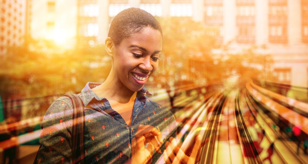 A smiling uses her phone on a street. Women's health is chronically under-funded and under-researched — but the Global Women's Health Alliance is changing that.