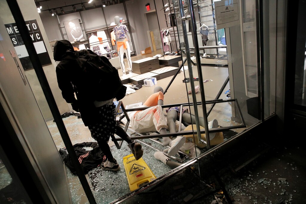 A person walks inside a damaged shop during a protest against the death in Minneapolis police custody of George Floyd, in Manhattan, New York, U.S., May 30, 2020. REUTERS/Andrew Kelly - RC2FZG94PL81