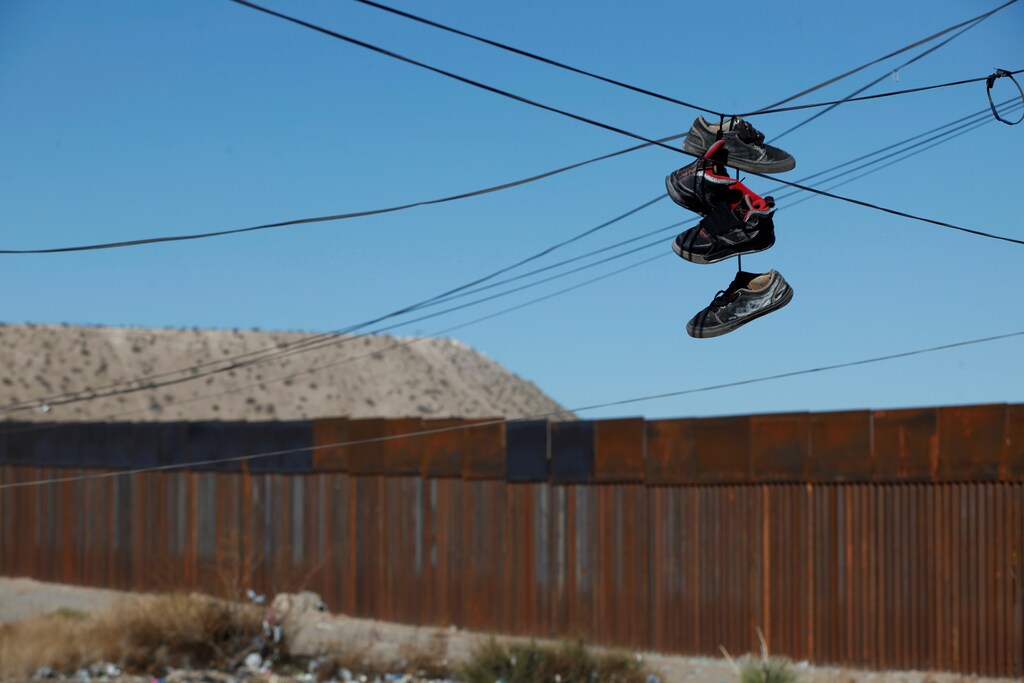 Sport shoes hang from a power line near a newly built section of the U.S.-Mexico border fence at Anapra neighbourhood in Ciudad Juarez, Mexico January 25, 2017. REUTERS/Jose Luis Gonzalez - RTSXCPH