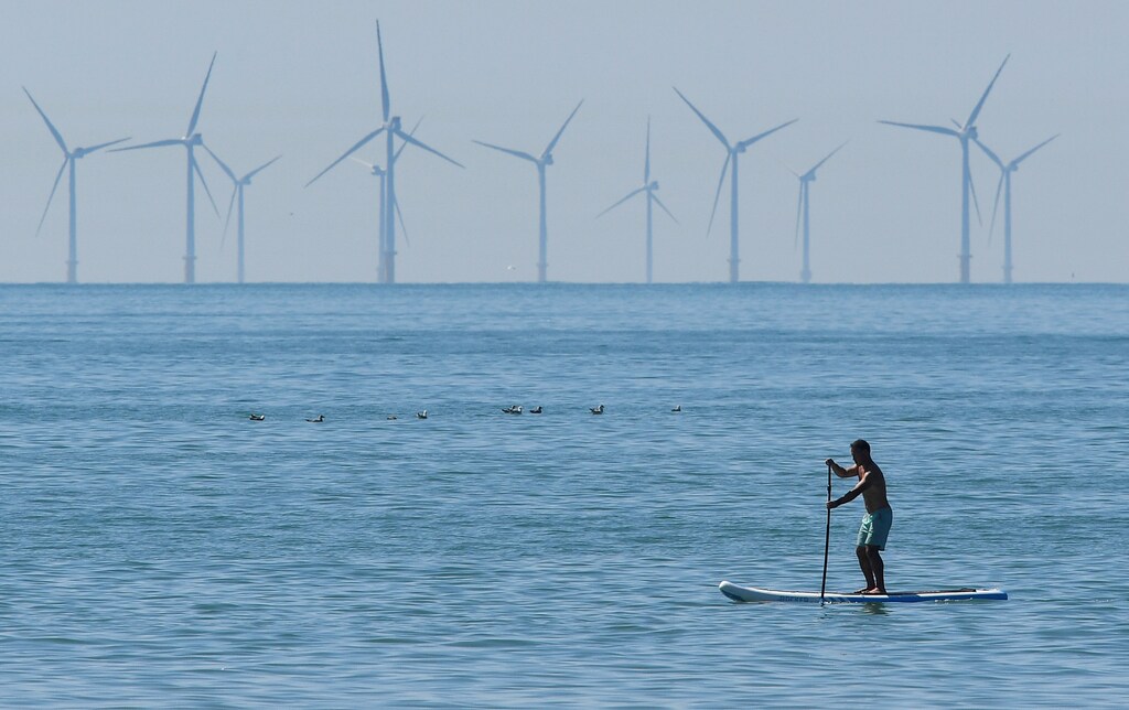 A man paddle boards, with an off-shore wind farm seen in the English Channel behind, during hot weather at Brighton in southern Britain, August 3, 2018. REUTERS/Toby Melville TPX IMAGES OF THE DAY - RC11BA0ACF10