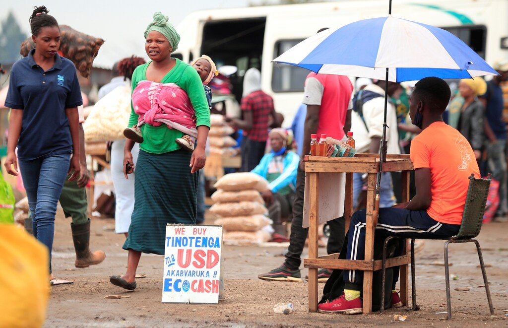 People walk past a money-changers sign at a market in Harare, Zimbabwe, November 26, 2020. REUTERS/Philimon Bulawayo - RC22BK9BQQFI