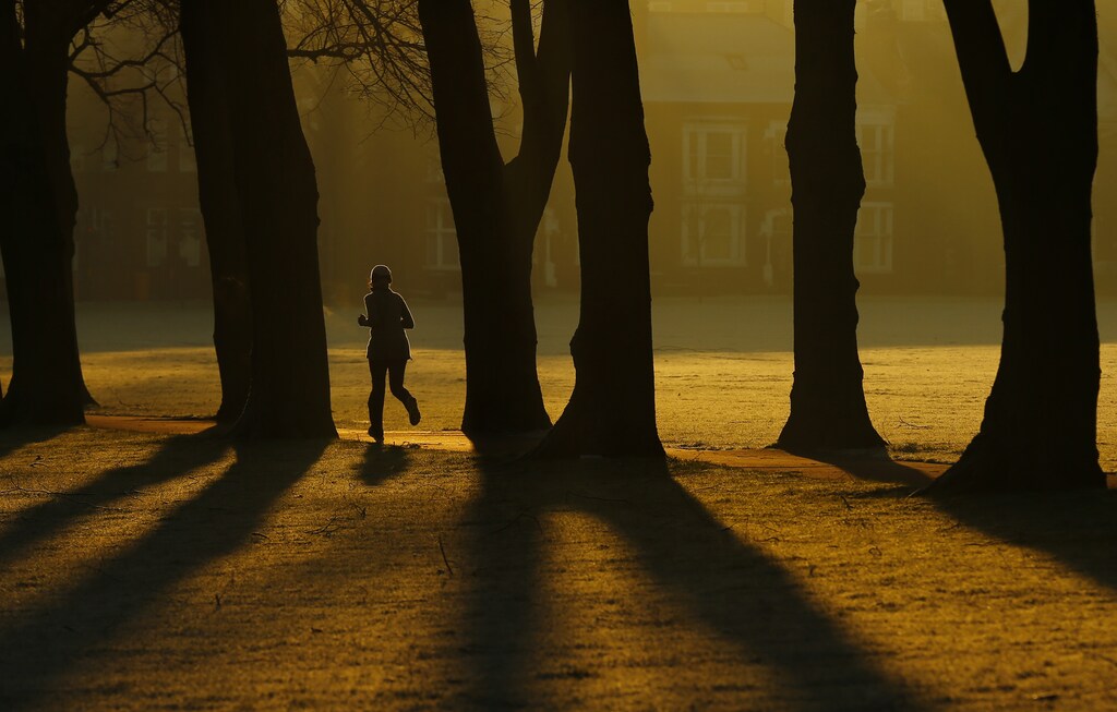 A woman runs through Victoria Park at sunrise in Leicester, central England, December 30, 2014. REUTERS/Darren Staples (BRITAIN - Tags: ENVIRONMENT SOCIETY TPX IMAGES OF THE DAY) - RTR4JLUZ
