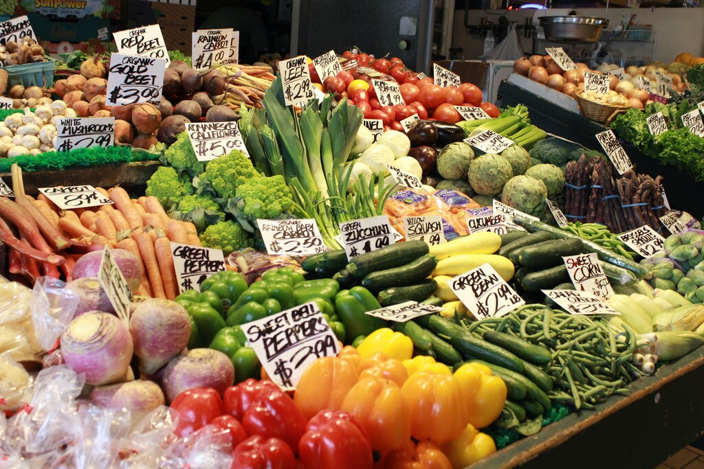 A range of vegetables with price cards at a market.