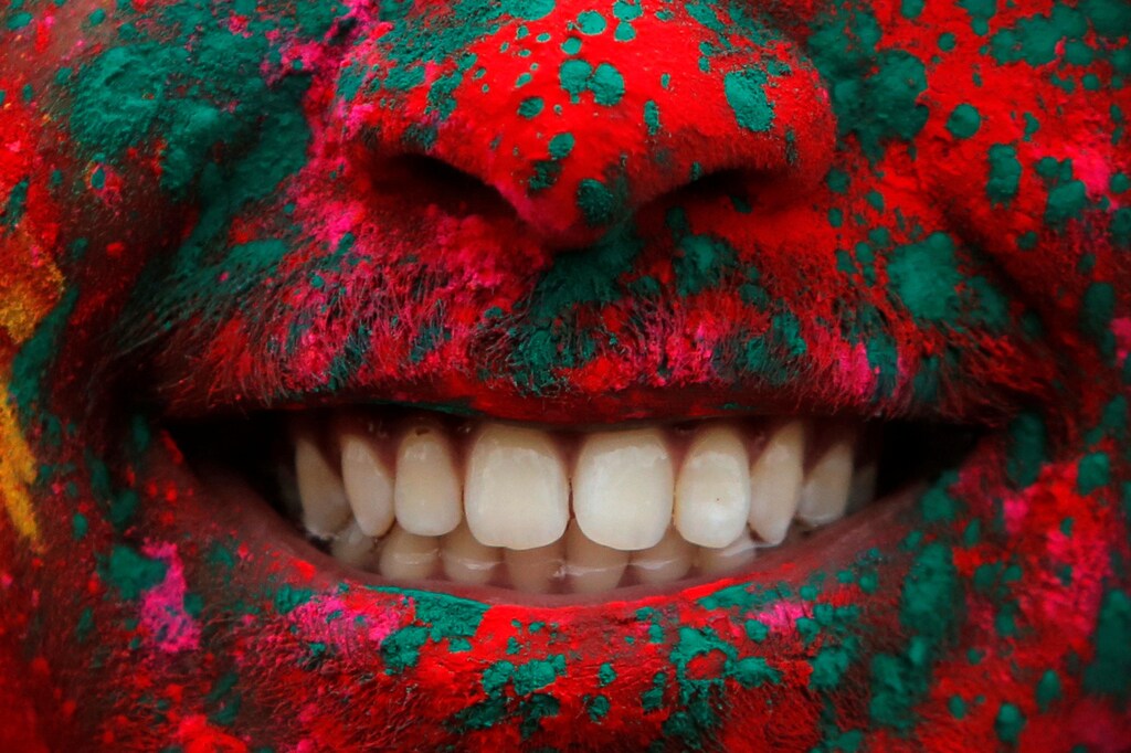 A person smiles after being covered in colored powder during a Holi festival party organized by Jai Jai Hooray and hosted by the Brooklyn Children's Museum in Brooklyn, New York, U.S., March 3, 2018. REUTERS/Andrew Kelly - RC15753B9E80
