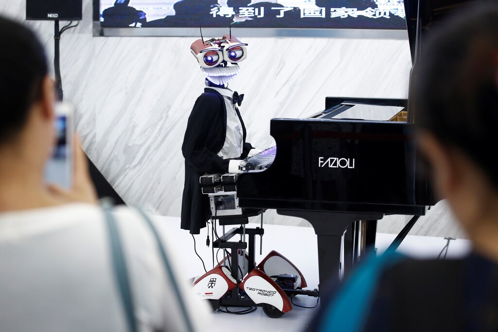 People watch the robot "Teo Tronico", designed by Matteo Suzzi, play piano and sing popular songs at the 2017 World Robot Conference in Beijing, China August 22, 2017. REUTERS/Thomas Peter - RC1D6A56ED80