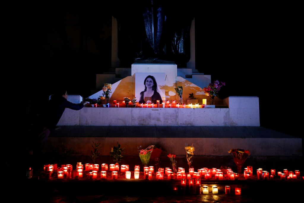 An activist places candles and flowers on the Great Siege monument, after rebuilding a makeshift memorial to assassinated anti-corruption journalist Daphne Caruana Galizia, during a vigil and protest to mark thirteen months since her murder, in Valletta, Malta November 16, 2018. REUTERS/Darrin Zammit Lupi - RC15B01C47A0