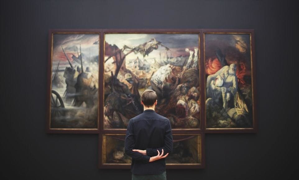 A person looking at a piece of art on a wall at a museum.
