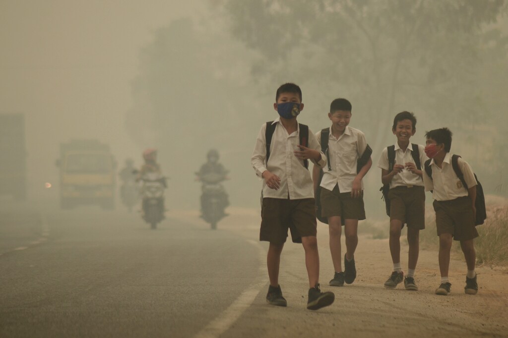 Students walk along a street as they are released from school to return home earlier due to the haze in Jambi, Indonesia's Jambi province, September 29, 2015 in this picture taken by Antara Foto. Indonesia has sent nearly 21,000 personnel to fight forest fires raging in its northern islands, the disaster management agency said on Tuesday, but smoke cloaks much of the region with pollution readings in the "very unhealthy" region in neighboring Singapore. REUTERS/Antara Foto/Wahdi Setiawan ATTENTION EDITORS - THIS IMAGE HAS BEEN SUPPLIED BY A THIRD PARTY. IT IS DISTRIBUTED, EXACTLY AS RECEIVED BY REUTERS, AS A SERVICE TO CLIENTS. FOR EDITORIAL USE ONLY. NOT FOR SALE FOR MARKETING OR ADVERTISING CAMPAIGNS. MANDATORY CREDIT. INDONESIA OUT. NO COMMERCIAL OR EDITORIAL SALES IN INDONESIA. - RTS275O