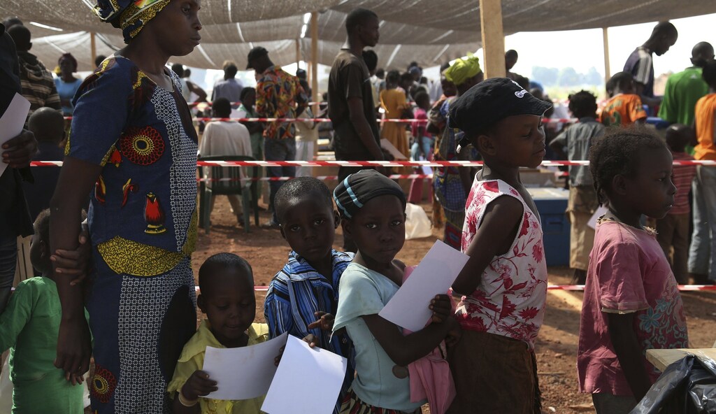 A woman and children wait to receive measles vaccinations operated by Médecins Sans Frontières (MSF) at Bangui airport camp January 8, 2014.