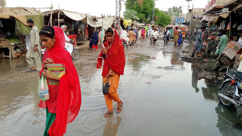 people in Pakistan walking through a flooded street
