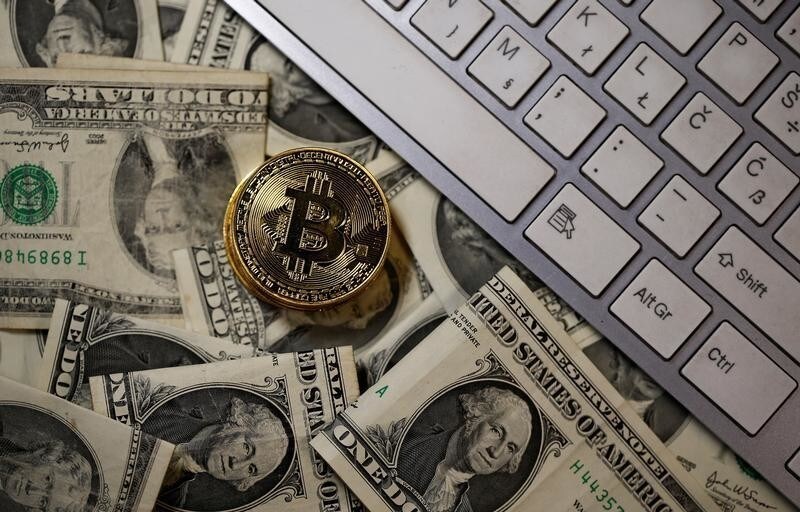 A bitcoin (virtual currency) coin placed on Dollar banknotes, next to computer keyboard, is seen in this illustration picture, November 6, 2017. REUTERS/Dado Ruvic/Illustration - RC1556E49EA0