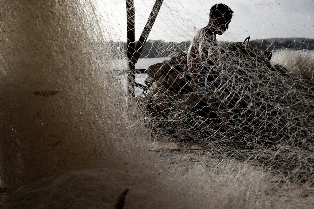 A fisherman works on his fishing net on the banks of the Oiapoque river in Oiapoque city, northern Brazil, April 2, 2017. REUTERS/Ricardo Moraes