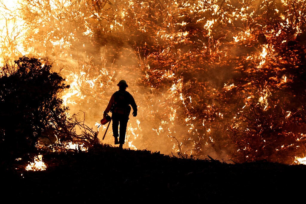 A firefighter works as the Caldor Fire burns in Grizzly Flats, California, U.S., August 22, 2021. Reuters photographer Fred Greaves: "As a photographer covering wildfires in California, 2021 was one of the most challenging years that I can remember. A severe multi-year drought along with sustained hot and windy weather created multiple âmega-firesâ that were unpredictable and quickly consumed hundreds of square miles. It can take hours to navigate around large wildfires in remote areas, so proper planning is critical to make sure you are in the right place. I also have to wear safety equipment and check on weather conditions and local fire activity so I donât become trapped. Firefighters were conducting a nighttime controlled burn to clear brush out after temperatures cooled and the wind had died down to protect homes that were potentially in the path of the Caldor Fire in Northern California. They lit backfires at the base of a hill, expecting it would burn at a moderate pace. Instead, the flames quickly raced up the side of the hill, creating the swirling curtain of fire that silhouetted one of the firefighters. It was yet another example of the unpredictable nature of wildfires." REUTERS/Fred Greaves/File Photo SEARCH "POY STORIES 2021" FOR THIS STORY. SEARCH "WIDER IMAGE" FOR ALL STORIES TPX IMAGES OF THE DAY