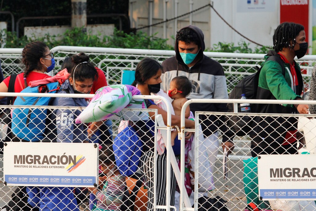 Venezuelan migrants wearing face masks line up at the Simon Bolivar border bridge after travelling on buses assigned by Colombian Migration office for their return to Venezuela, amid the coronavirus disease (COVID-19) outbreak, in Cucuta, Colombia April 15, 2020. REUTERS/Mario Caicedo. NO RESALES. NO ARCHIVES. - RC2C5G9U0BRL