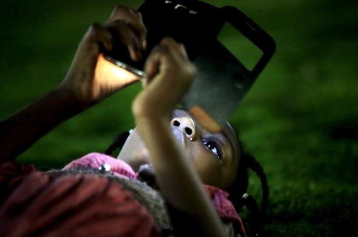 A girl uses her mobile phone during the evening at the National Park in Khartoum, Sudan, April 24, 2015. In Sudan, which faces insurgences in the western region of Darfur and along its border with breakaway South Sudan, as well as double-digit inflation and high unemployment, life goes on for young people in the capital Khartoum. As well as studying, for those who can afford it, the urban young of Sudan play football and netball, swim and fish in the nearby River Nile, attend prayers at local mosques and enjoy concerts or family celebrations. Other entertainment includes watching U.K. football matches and films on TV, with Facebook being ever popular for chatting amongst friends. REUTERS/Mohamed Nureldin AbdallahPICTURE 26 OF 28 FOR WIDER IMAGE STORY "YOUTH OF TODAY IN SUDAN". SEARCH "YOUNG NURELDIN" FOR ALL IMAGES