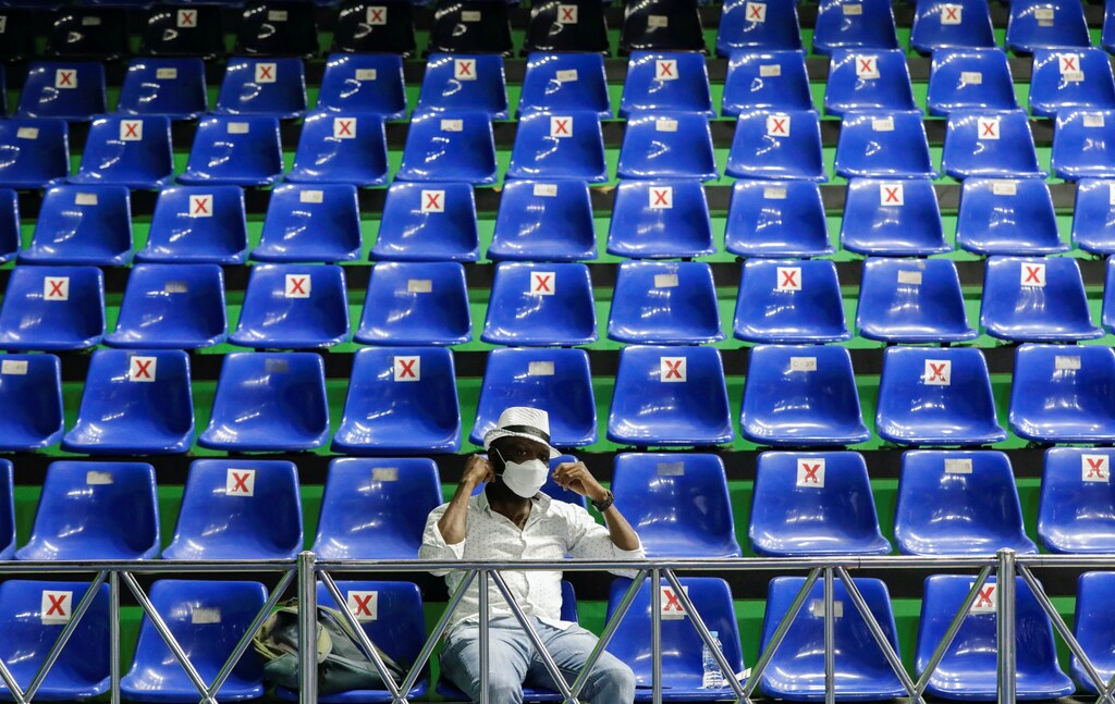 A man wearing a protective face mask sits inside a sports hall as he waits to receive a dose of a vaccine against the coronavirus disease (COVID-19) during a mass vaccination program for asylum seekers and refugees in Jakarta, Indonesia, October 7, 2021.