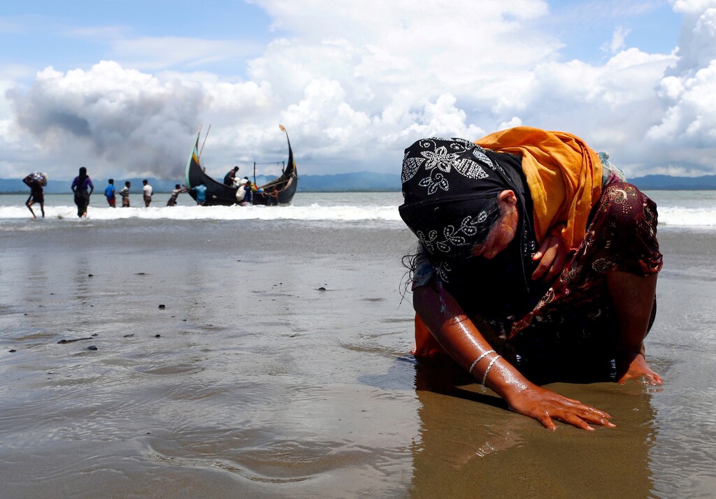 An exhausted Rohingya refugee woman touches the shore after crossing the Bangladesh-Myanmar border by boat through the Bay of Bengal, in Shah Porir Dwip, Bangladesh September 11, 2017. Reuters photographer Danish Siddiqui: "It was a clear morning and I could see the several clouds of smoke in the background on the Myanmar side. After a few hours waiting on the beach the fishing boats started arriving with Rohingyas. This image was taken just after a family member of the Rohingya woman carried her from the boat. The exhausted Rohingya woman sat on the beach and put her hand to feel the shore after the long and dangerous journey from Myanmar." REUTERS/Danish Siddiqui/File Photo SEARCH "POY ROHINGYA" FOR THIS STORY. SEARCH "REUTERS POY" FOR ALL BEST OF 2017 PACKAGES. TPX IMAGES OF THE DAY. - RC1FA77239A0