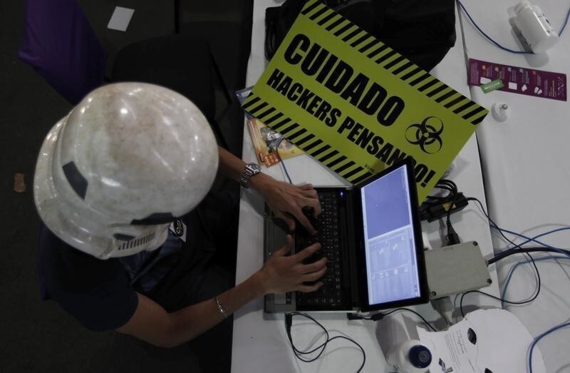 A man uses a laptop during a "Campus Party" Internet users gathering in Sao Paulo January 30, 2013. Campus Party is an annual week-long, 24-hour technology festival that gathers around 8000 hackers, developers, gamers and computer geeks from around the world. The banner (in yellow) reads "Watch out, Hackers thinking".