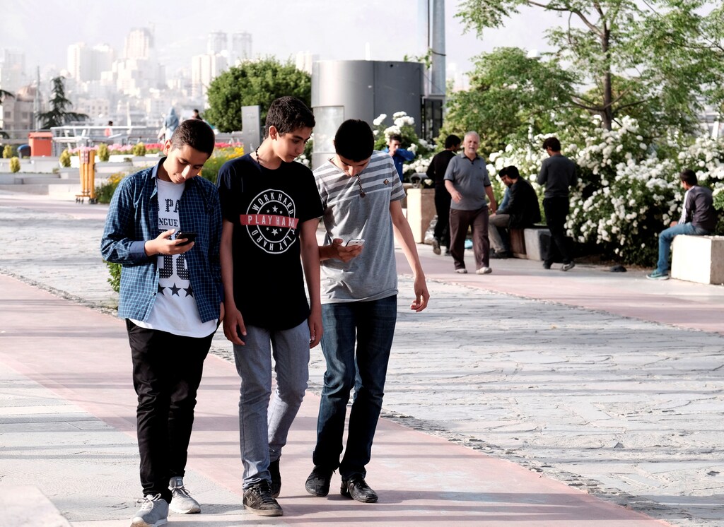 Iranian youth use their mobile phones as they walk at a park in Tehran, Iran, May 16, 2017. REUTERS/TIMA ATTENTION EDITORS - THIS IMAGE WAS PROVIDED BY A THIRD PARTY. FOR EDITORIAL USE ONLY. - RTX3636P
