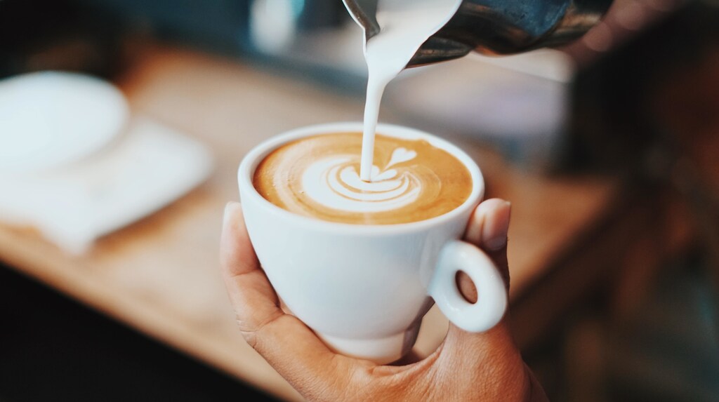 A person pouring milk into a cup of coffee. Impact of inflation: Eurostat data shows that the price of a cup of coffee rose by 16.9% in the year to August 2022.