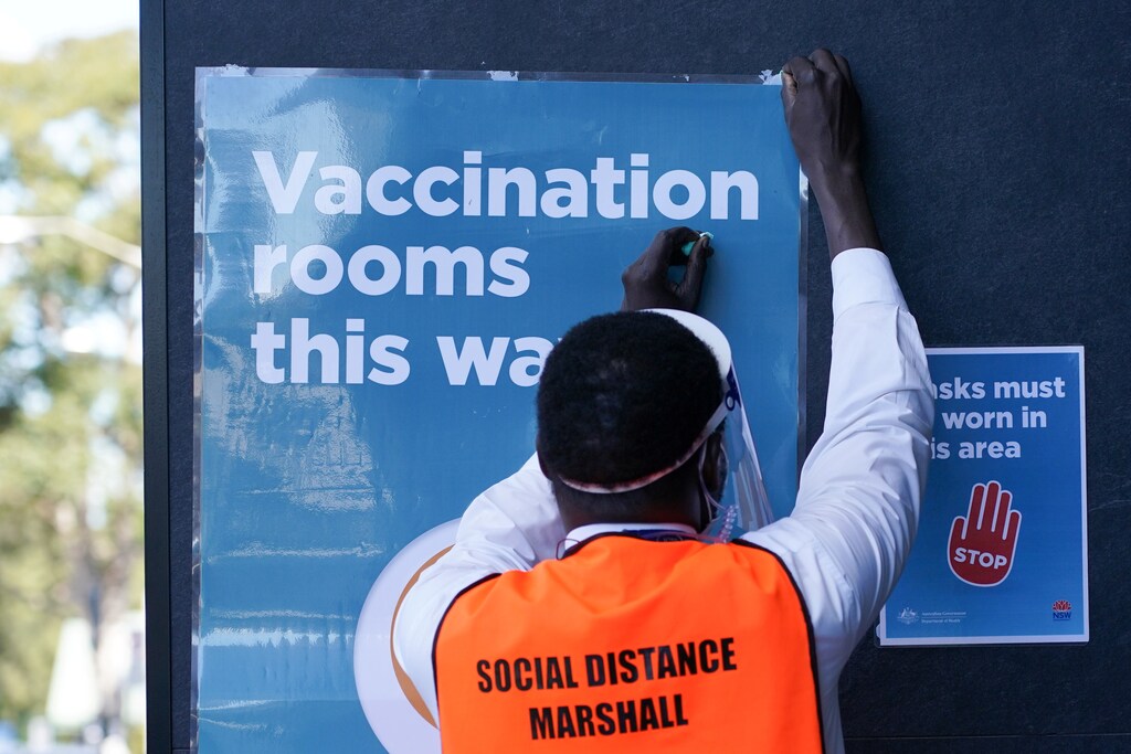 A staff member straightens a sign outside a coronavirus disease (COVID-19) vaccination clinic at the Bankstown Sports Club as the city experiences an extended lockdown, in Sydney, Australia, August 3, 2021. REUTERS/Loren Elliott - RC2EXO9LXBD1
