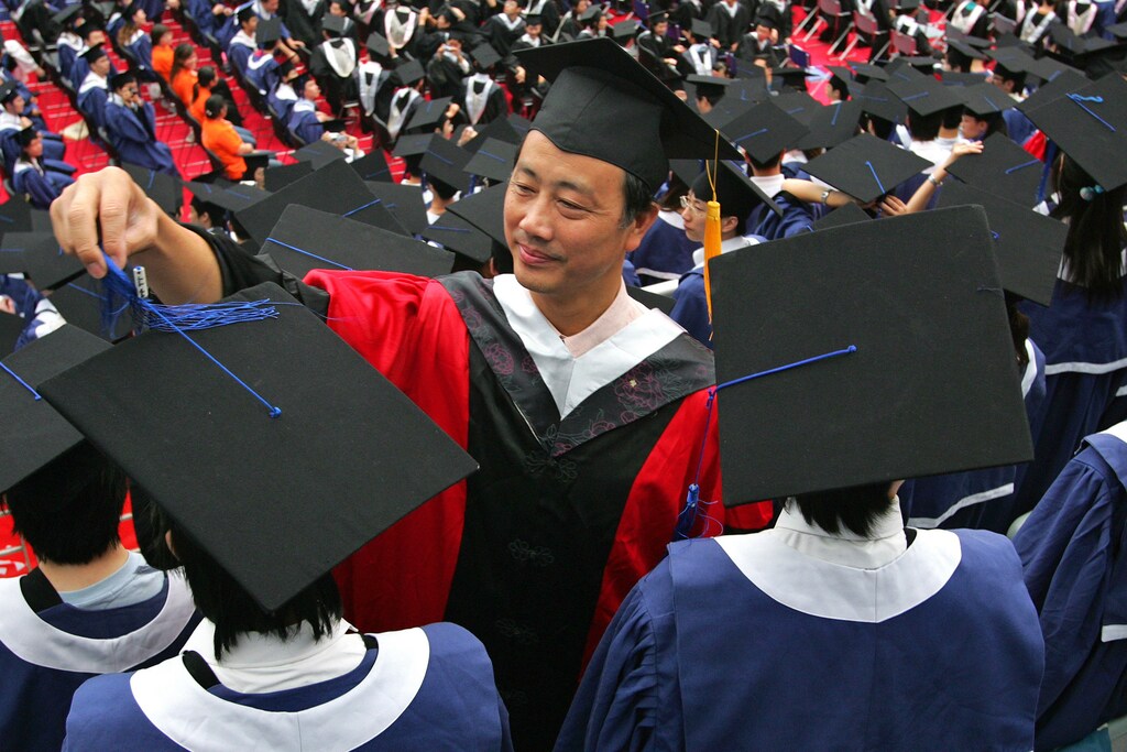 A man adjusts a student's mortar board during the graduation ceremony at Fudan University in Shanghai June 28, 2006. With about 750,000 more students graduating into the workforce this year compared to last, the competition is getting tougher, leaving the 20-somethings whose studies have often left them with little practical know-how floundering to find work. Picture taken June 28, 2006. TO MATCH FEATURE CHINA GRADUATES REUTERS/Aly Song (CHINA) - GM1DSYEPDMAA