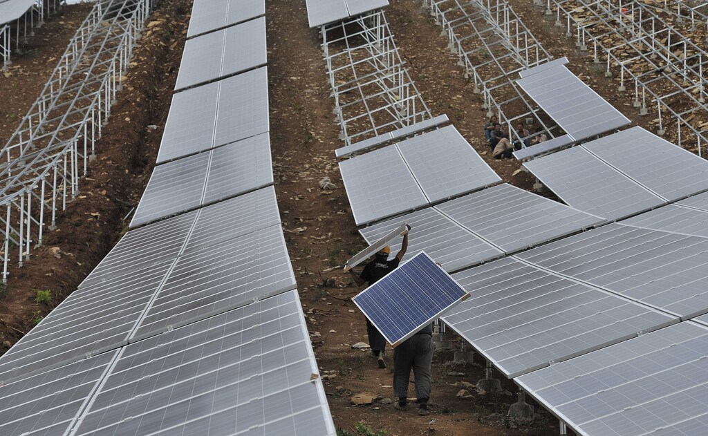 Workers carry solar panels at a solar power plant in Anhui province, China