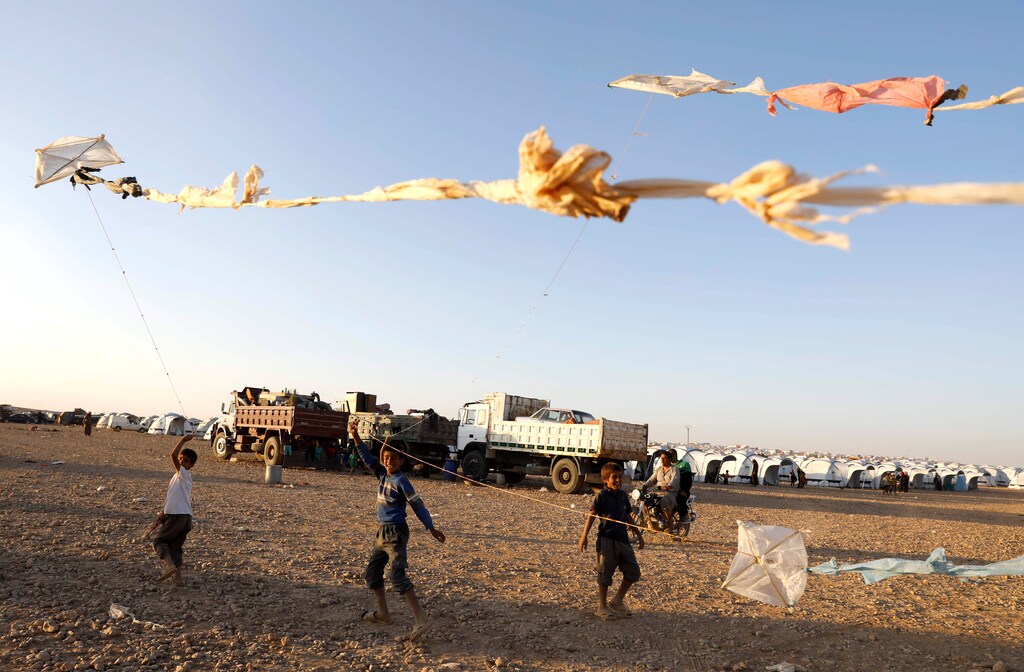 Children fly their kites as they play inside a refugee camp for people displaced by fightings between the Syrian Democratic Forces and Islamic State militants in Ain Issa, Syria October 3, 2017. REUTERS/Erik De Castro - RC1C3D183EB0