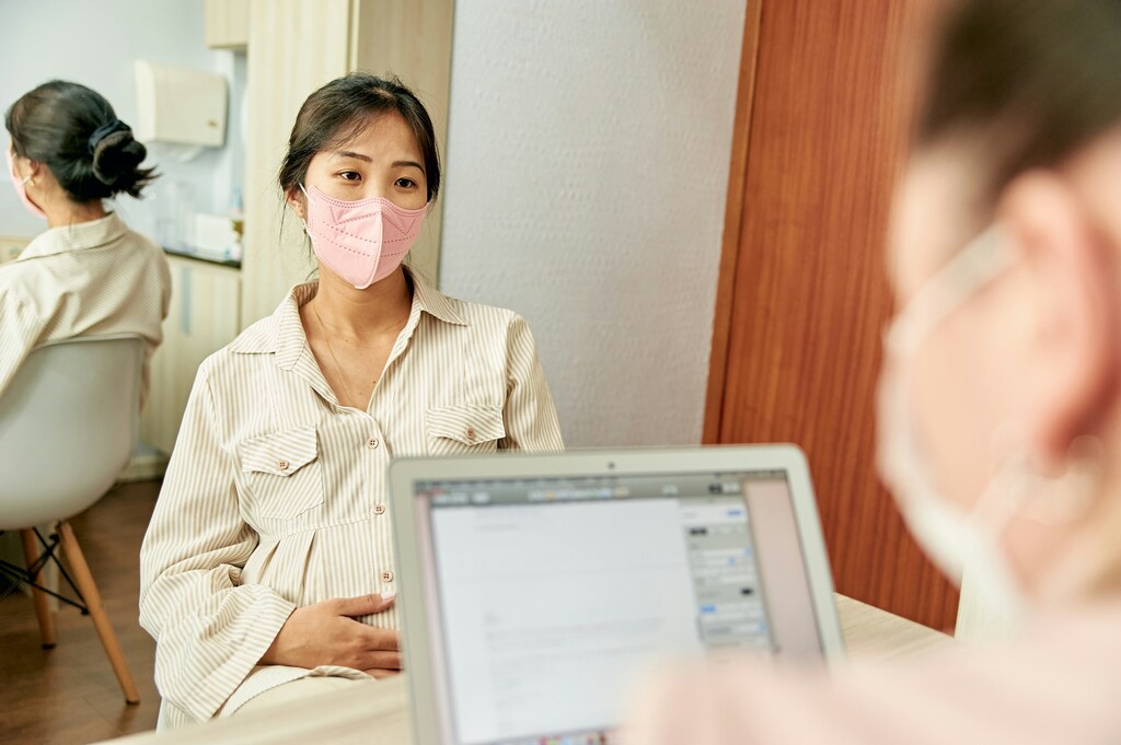 A pregnant woman sits opposite a desk with laptop: Targeted policy can health address the women’s health research gap
