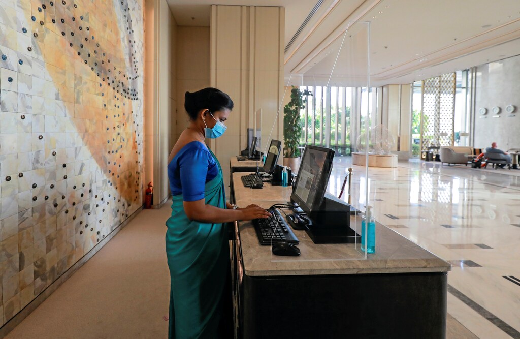 A receptionist wearing a protective mask is seen behind a protective screen at the main entrance of the Shangri-La hotel, amid concerns about the spread of the coronavirus disease (COVID-19), in Colombo, Sri Lanka, July 1, 2020. REUTERS/Dinuka Liyanawatte - RC2EKH98LCDQ