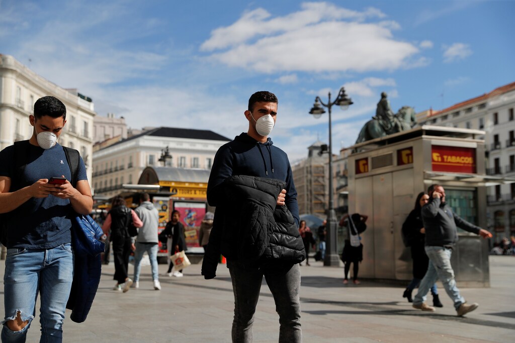 Hombres llevan máscaras protectoras cuando caminan por la plaza de la Puerta del Sol en Madrid, España, el 4 de marzo de 2020.