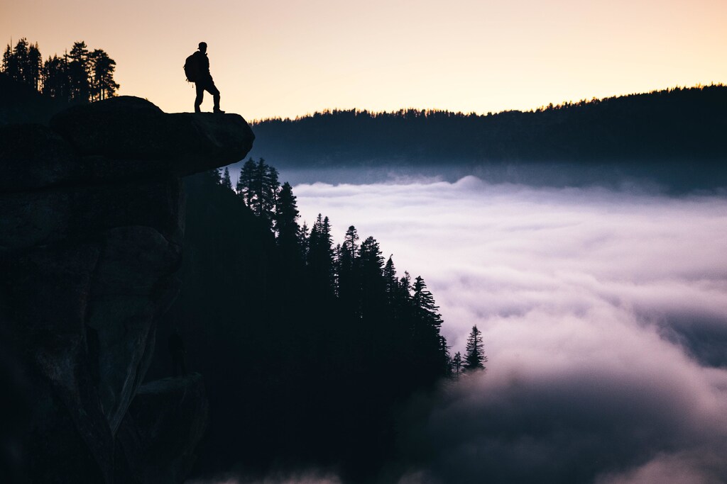Person on cliff, forest, mist, sunset; tipping points for sustainable investment
