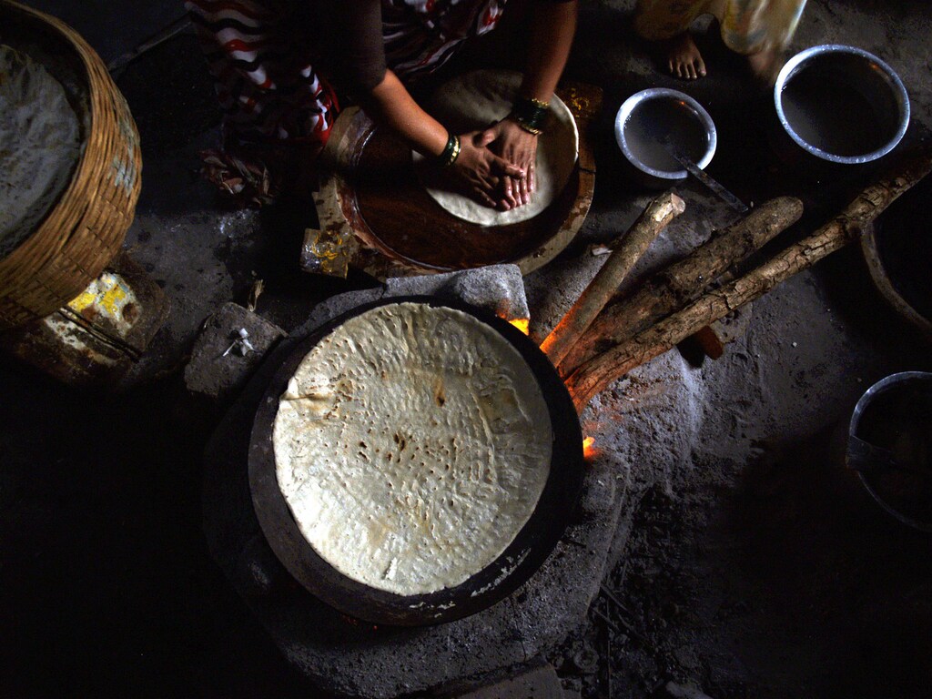 An Indian fisherwoman prepares a meal on a wood-burning stove in her home near Mumbai