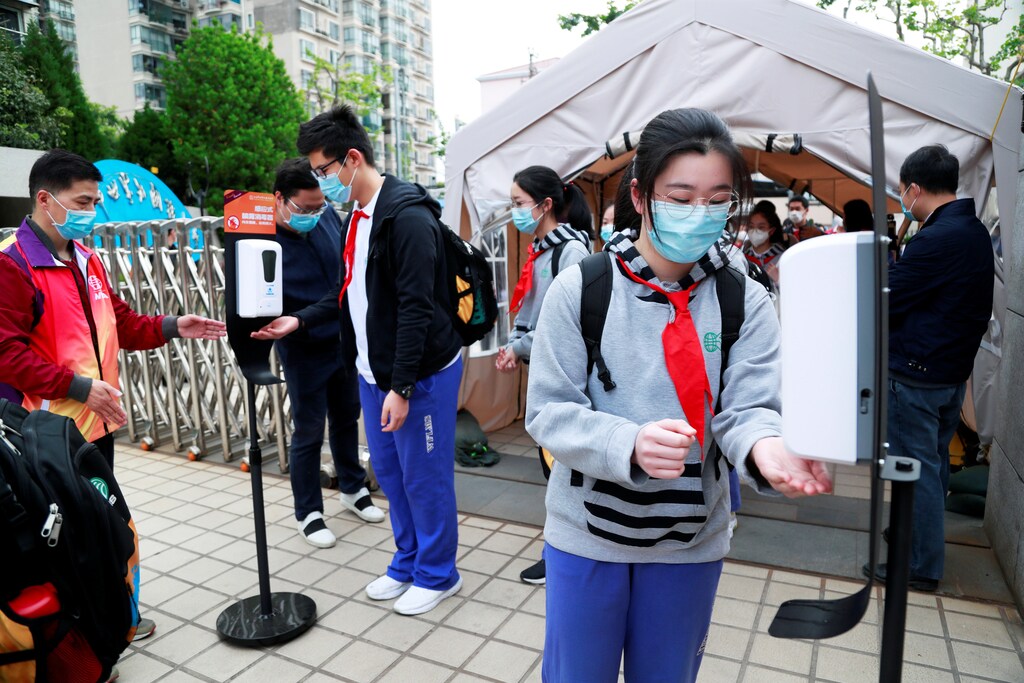 Students wearing face masks use hand sanitisers at an entrance to a school in Shanghai, China, as senior high school and senior middle school students in Shanghai return to campus following the coronavirus disease (COVID-19) outbreak, April 27, 2020. cnsphoto via REUTERS ATTENTION EDITORS - THIS IMAGE WAS PROVIDED BY A THIRD PARTY. CHINA OUT. - RC2SCG9A3Y1I