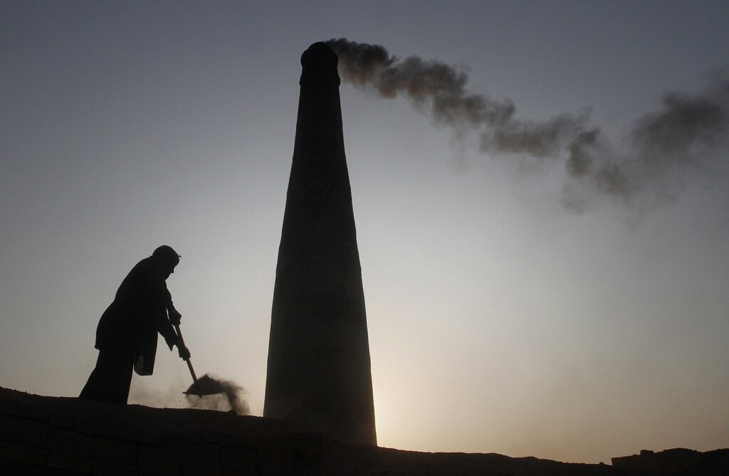 A man removes dirt from an oven to retrieve baked bricks at a brickyard in the outskirts of Islamabad December 28, 2011.