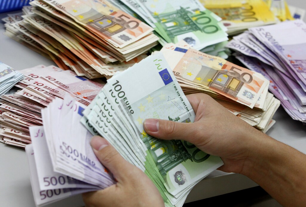A bank employee counts Euro notes at Kasikornbank in Bangkok .