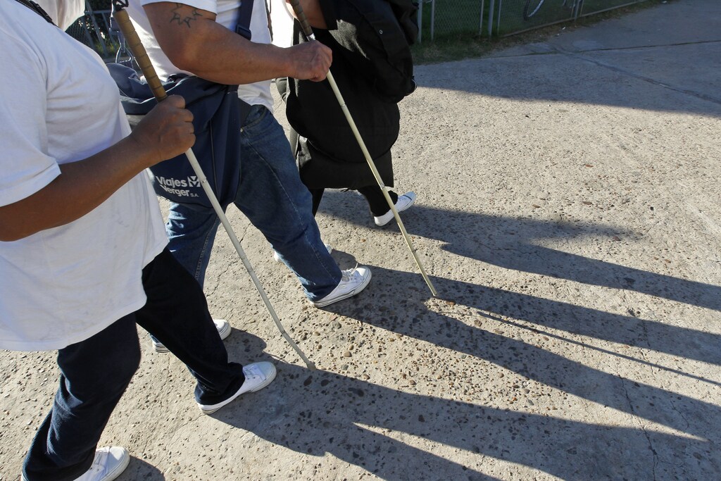 Eusebia Casimiro (L), who was left blind as an adult during surgery to remove a brain tumour, and her husband Leonardo Duarte (C), also blind, walk to a bus as they travel to perform in a Carnival street theatre called "murga", in Buenos Aires, April 20, 2013. Leonardo and Eusebia are two of around 400,000 blind people in Argentina, who despite having their lives improved through the legalization of guide dogs in more public places, still face a lack of jobs, a major problem according to the Association for Aid to the Blind. Picture taken April 20, 2013. REUTERS/Enrique Marcarian (ARGENTINA - Tags: SOCIETY HEALTH) - GM1E9AM00GX01