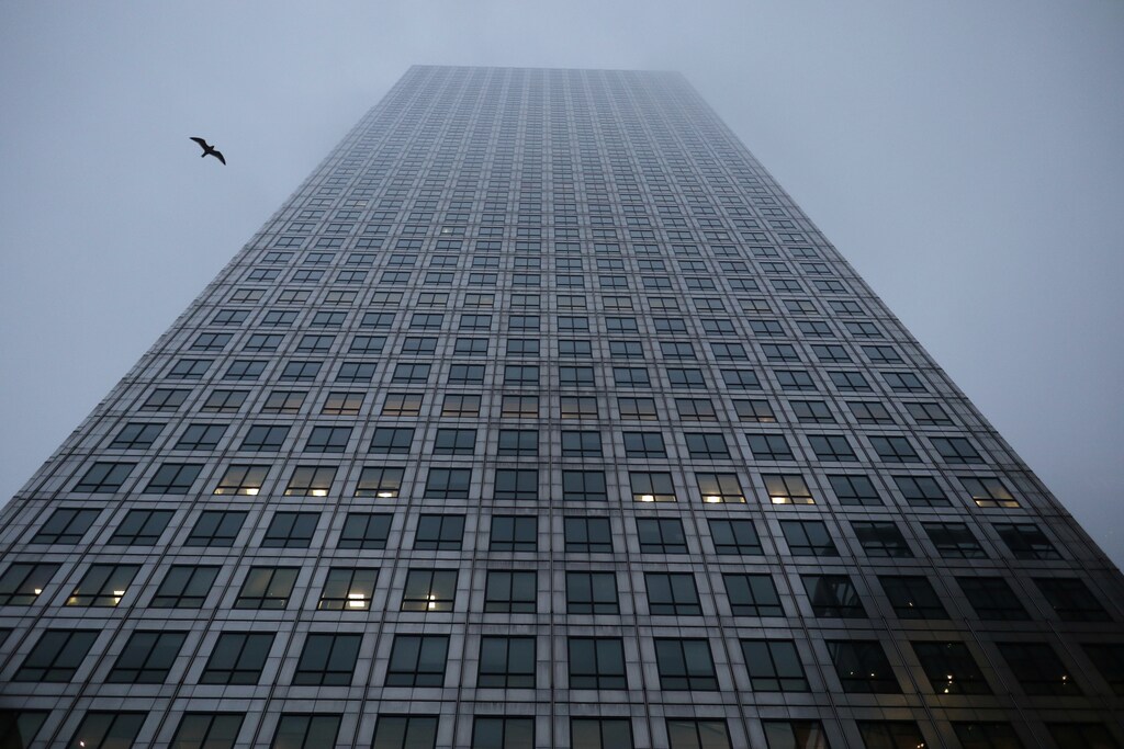 A bird flies between the buildings in the early morning mist in London's Canary Wharf financial district, Britain March 28, 2017. REUTERS/Russell Boyce - RC17DA90A520
