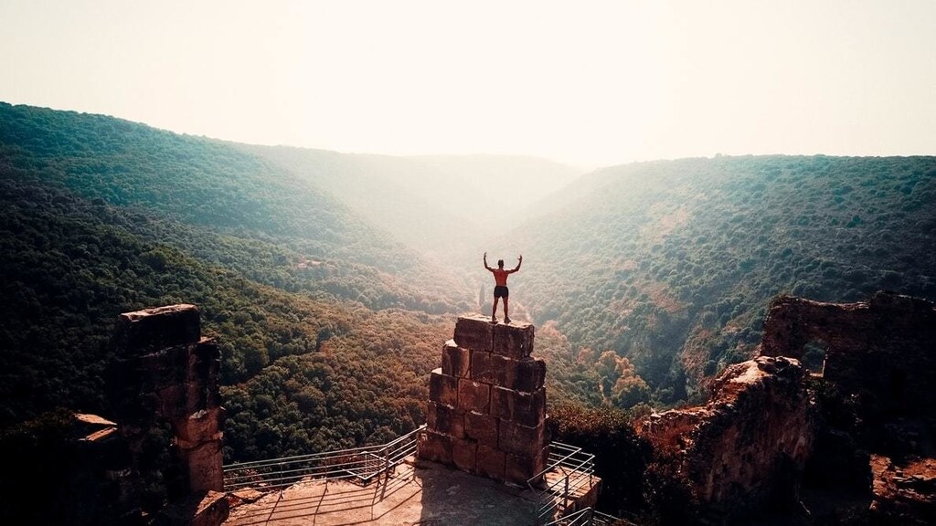 A man stands on top of rocks, overlooking the mountains.
