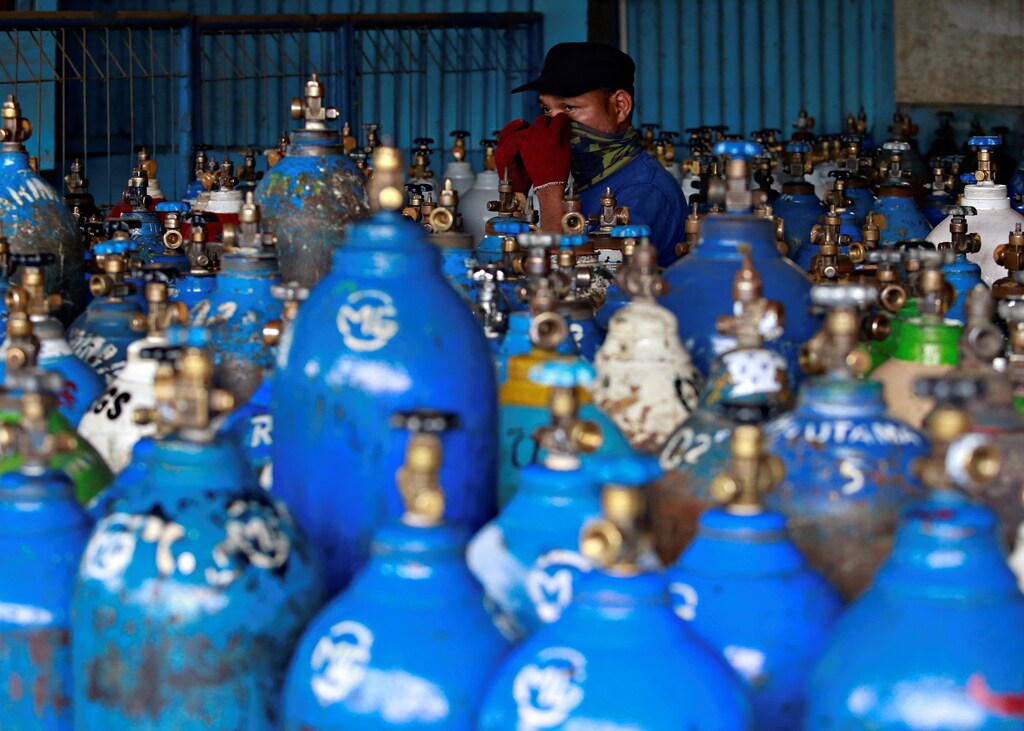 An employee adjusting a scarf on his face walks near oxygen cylinders at a factory amid the coronavirus disease (COVID-19) outbreak in Jakarta, Indonesia, June 29, 2021. REUTERS/Ajeng Dinar Ulfiana TPX IMAGES OF THE DAY - RC29AO9RVWS6